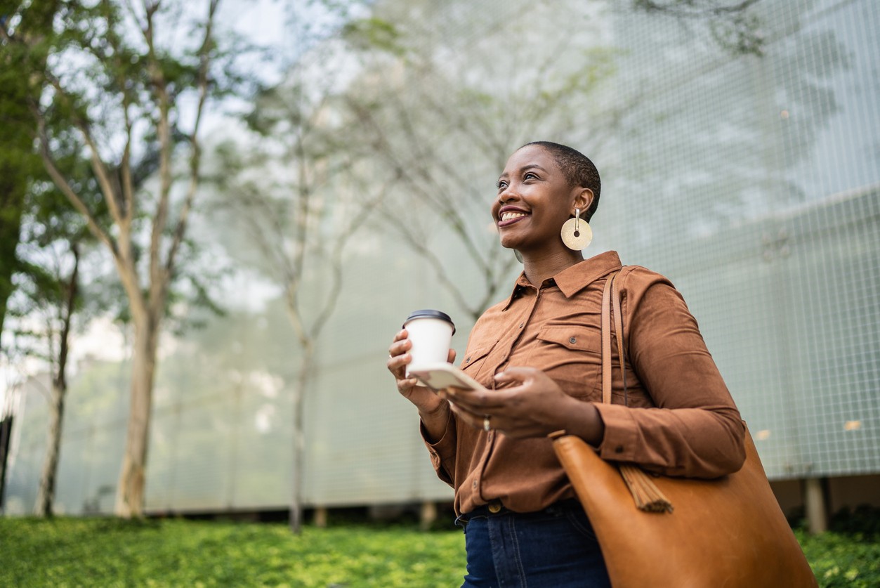 Business woman holding smartphone and looking away outdoors