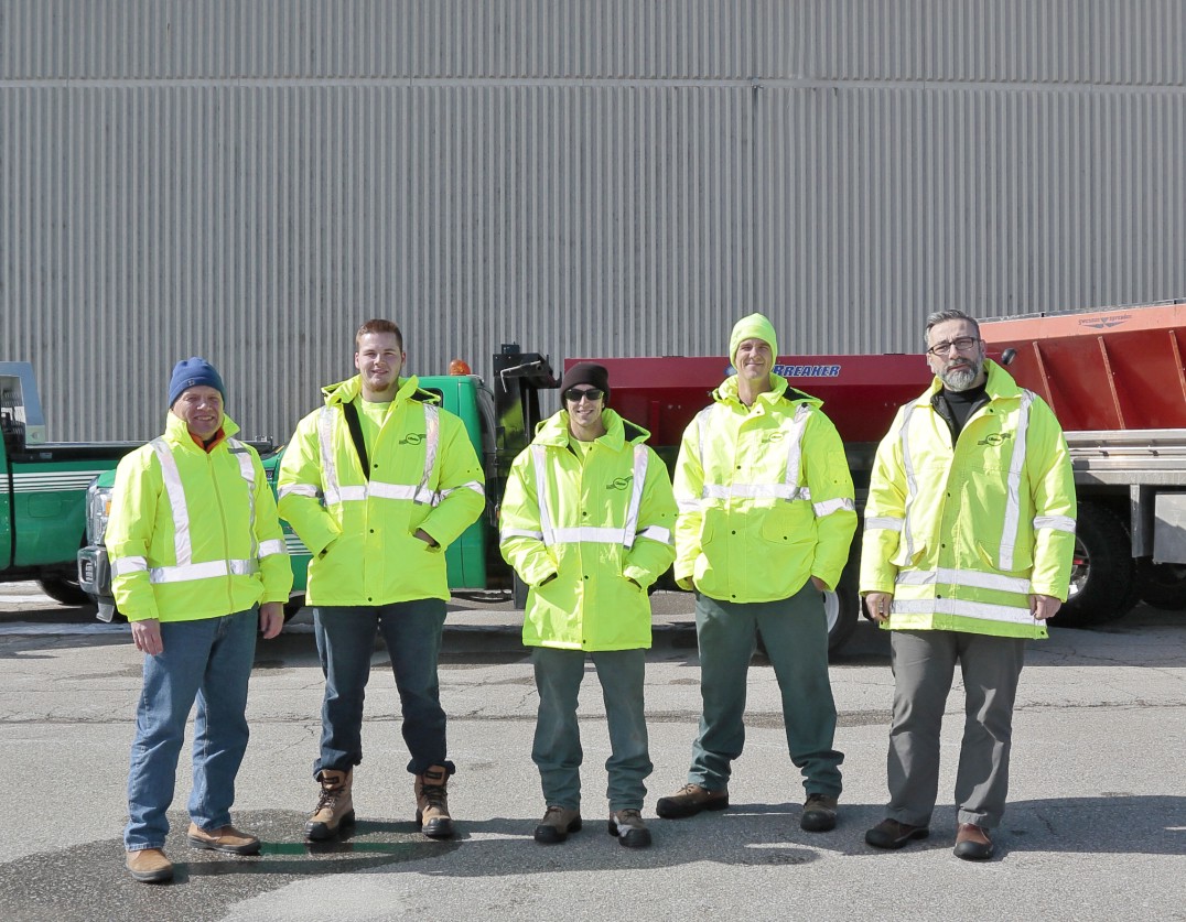 Five Clintar staff members in bright yellow reflective jackets stand in front of a truck.